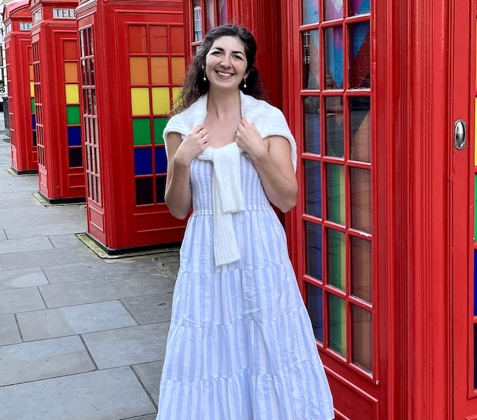 Nicole Sauter stands in front of telephone booths decorated in rainbow colors